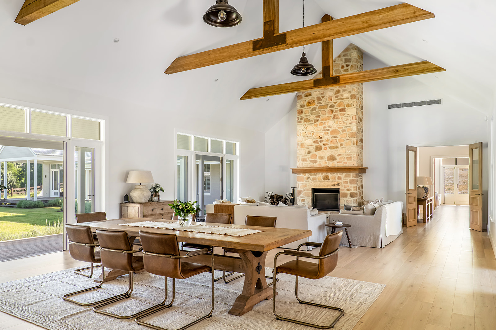 Possum Creek interior — vaulted timber-beamed ceiling, fieldstone fireplace and French doors opening onto the verandah